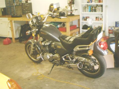 1989 Ford Bronco - Motorcycle parked in a garage with tools and shelves in the background.