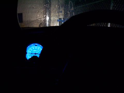 1995 Ford Crown Victoria - The interior of a vehicle at night, showing a dimly lit dashboard with a bright blue illuminated gauge.
