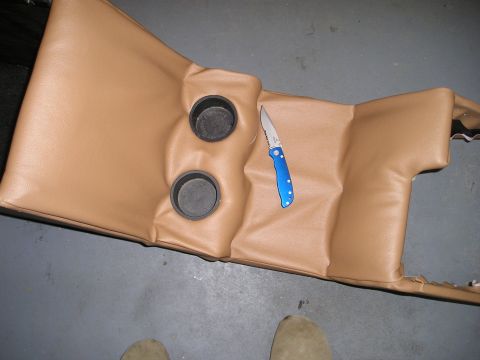 1996 Ford Bronco - Center console with cup holders and a knife, likely from a vehicle interior.
