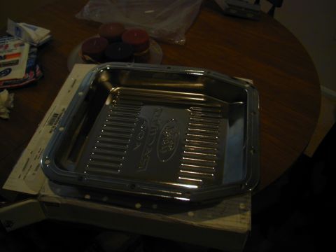 1988 Ford Bronco - Chrome transmission pan with Ford logo embossed, sitting on a table.