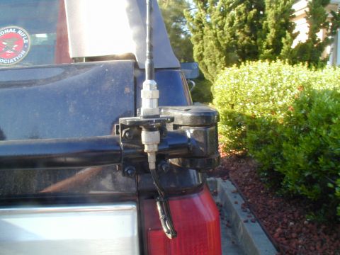 1988 Ford Bronco - Antenna mount assembly on the rear of a dark SUV, an NRA sticker on the side.