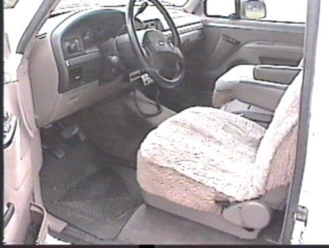 1993 Ford Bronco - The interior of a truck shows the driver's side dashboard, steering wheel, and a fuzzy seat cover.