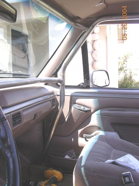 1994 Ford Bronco - The interior of a vehicle is visible, a custom roll cage structure and the dashboard area.
