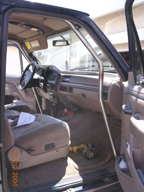 1994 Ford Bronco - Interior of a Ford truck, likely a Bronco or F-series, with a custom roll cage and tools on the floor.
