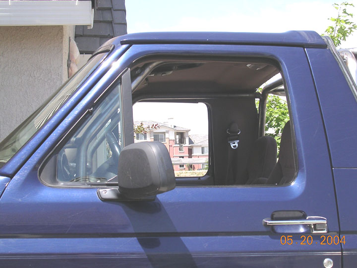 Dark blue Ford Bronco side view with window down showing interior roll bar