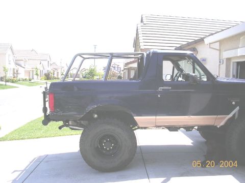 1994 Ford Bronco - This 1994 Ford Bronco features a custom roll cage and tan body trim, seen from the side.