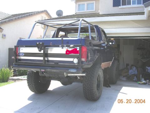 1994 Ford Bronco - Ford Bronco with aftermarket roll cage and off-road tires, viewed from the rear.