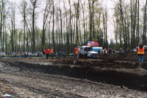 1990 Ford Bronco - Mud bogging event with trucks stuck in mud and spectators watching.