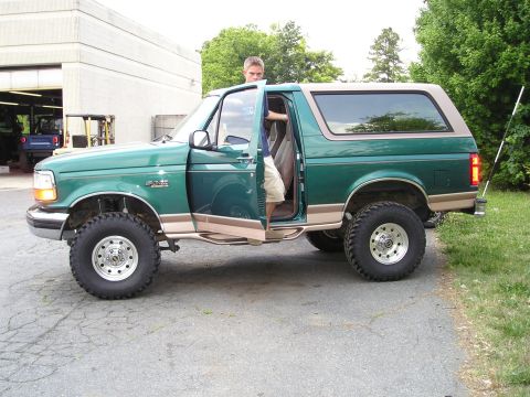1996 Ford Bronco - This lifted 1996 Ford Bronco features green paint with tan trim and prominent running boards.