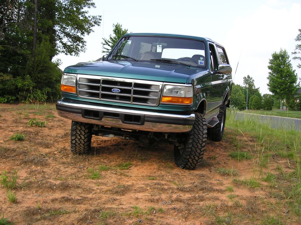 Green 1996 Ford Bronco with lifted suspension parked on dirt