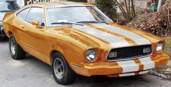 Orange coupe with white racing stripes, front quarter view. Visible front grille, headlights, and side mirror