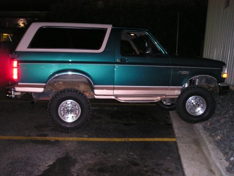 1996 Ford Bronco - Lifted 1996 Ford Bronco parked on a curb at night.