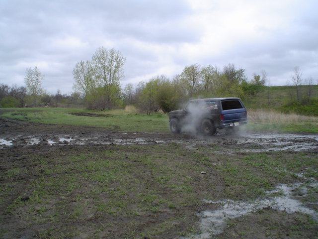 Blue SUV kicking up dust while driving through mud