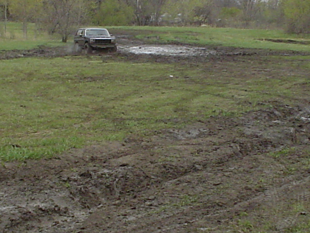 SUV driving through a muddy field, kicking up water