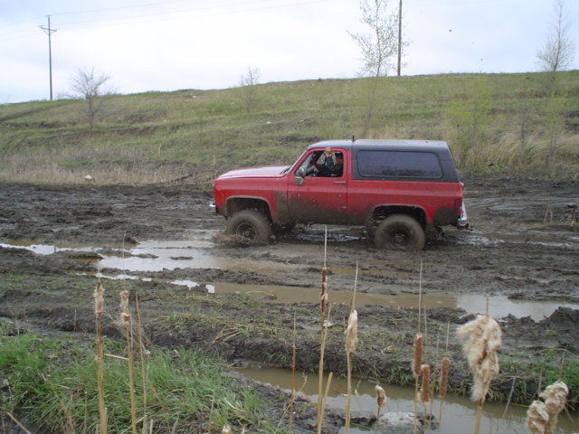 Red Chevrolet K5 Blazer stuck in mud, side view. Model years 1973-1991