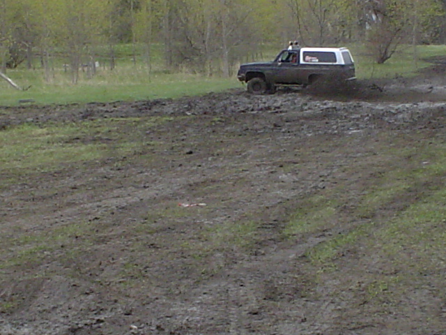 Dark SUV with white top driving through mud. 1981 Ford Bronco