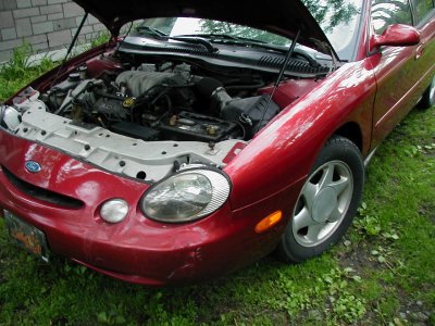 1997 Ford Taurus - Front view of a red 1997 Ford Taurus with the hood open, parked on grass.