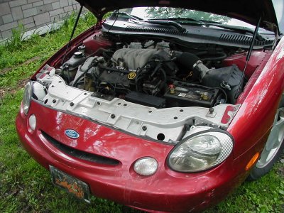 1997 Ford Taurus - The engine bay of a red 1997 Ford Taurus is displayed with the hood open.