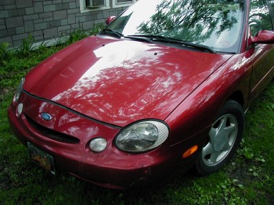 1997 Ford Taurus - A red 1997 Ford Taurus is shown from a three-quarter front angle, parked outdoors on a grassy lawn.