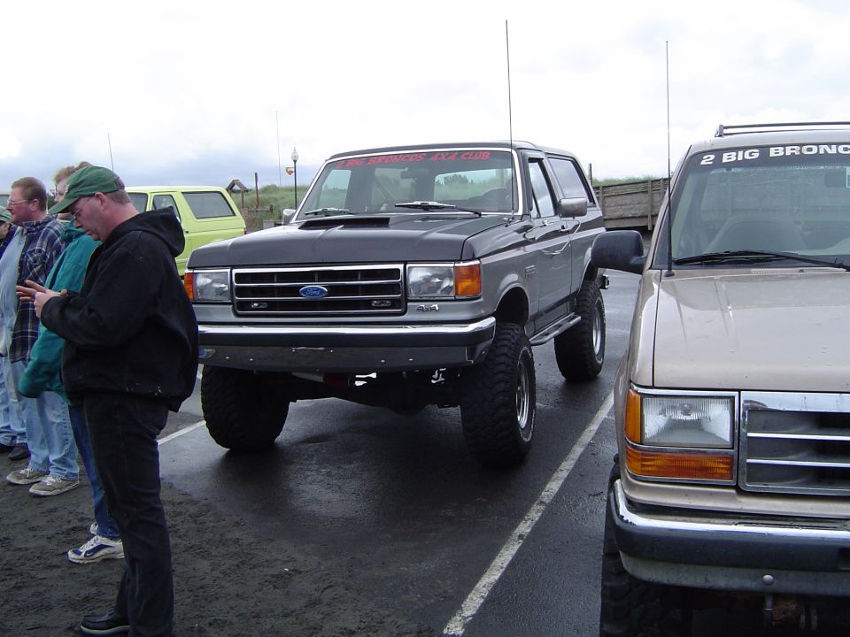 Lifted Ford Bronco with a banner on top, parked next to another SUV