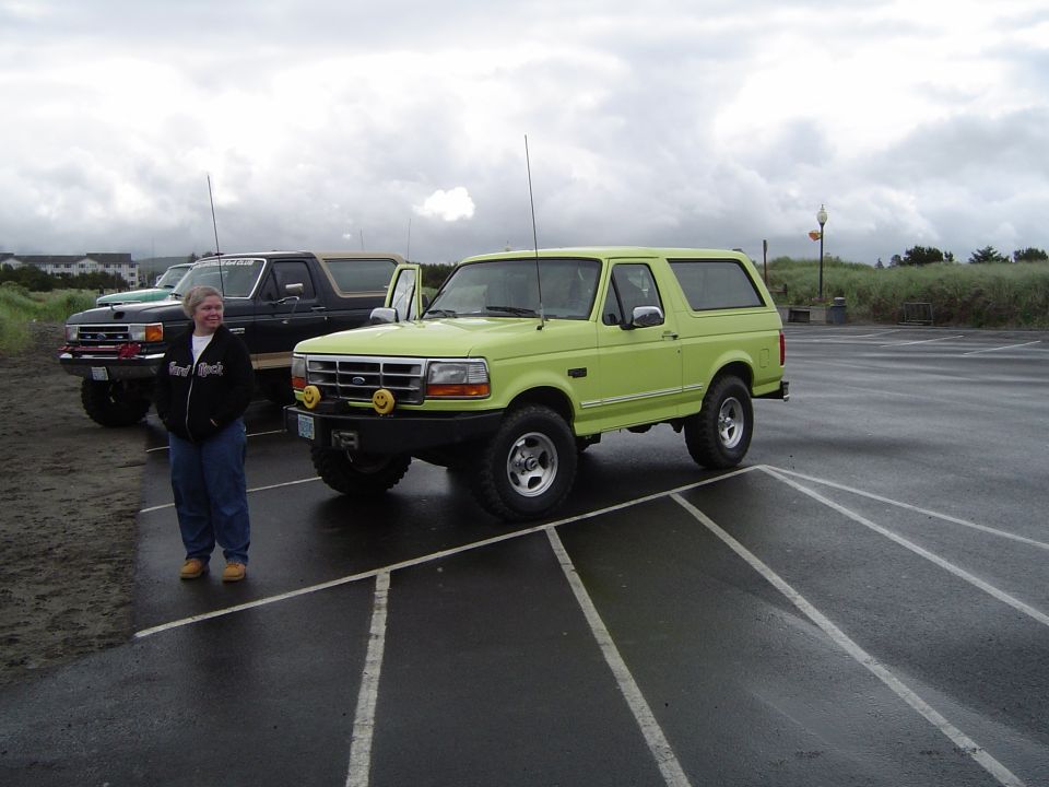 Lime green Ford Bronco parked on wet asphalt, driver's door open