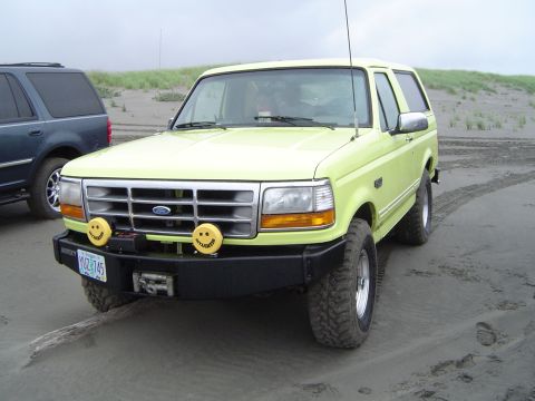 1989 Ford Bronco - This 1989 Ford Bronco, equipped with custom smiley face fog lights, is parked on a sandy beach next to another SUV.