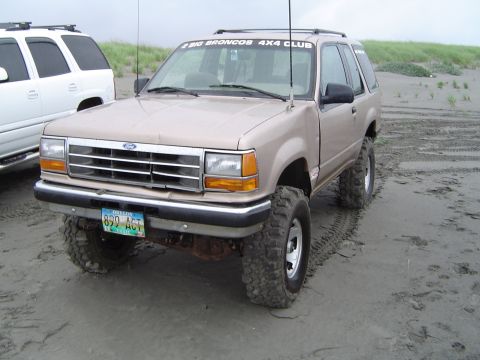 1989 Ford Bronco - This Ford Explorer, modified for off-road use, is parked on a sandy beach with another SUV nearby.