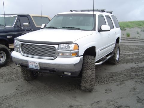 1989 Ford Bronco - A white SUV is parked on a sandy terrain next to another vehicle.