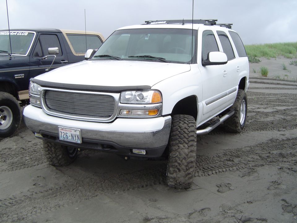 White SUV with chrome grille and off-road tires on sand