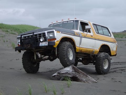 1989 Ford Bronco - This modified Ford Bronco is shown on a beach with a large piece of driftwood under its front tire.