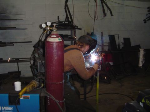 1993 Ford Bronco - A welder is actively working on a metal project, illuminated by the bright sparks from the torch.