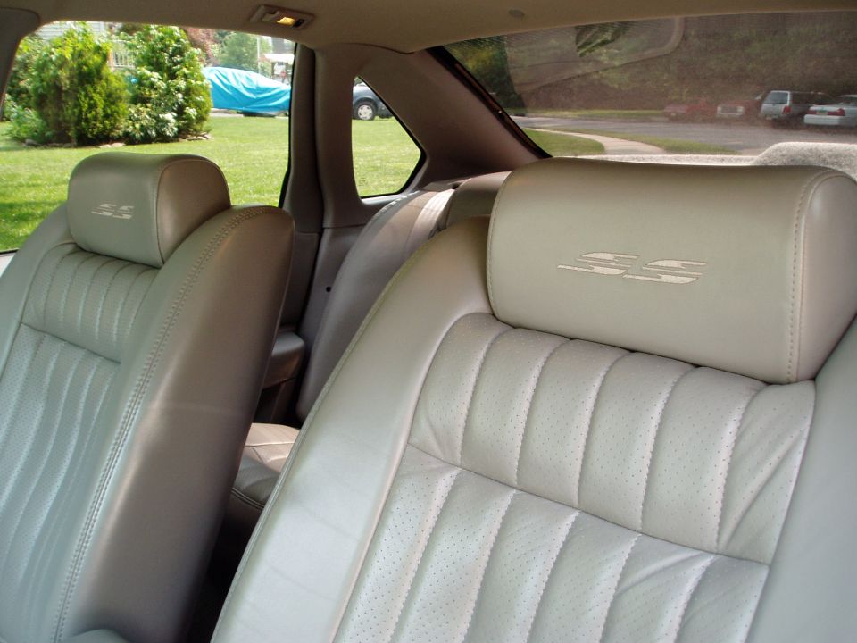 Tan leather car seats with SS embroidered headrests, viewed from rear