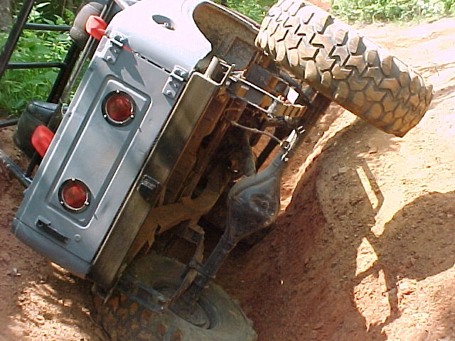 Silver 1978 Ford Bronco overturned on its side on a dirt trail