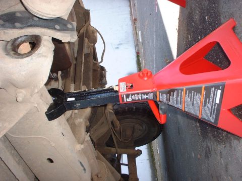 1983 Ford Bronco - A vehicle's undercarriage is shown supported by a red jack stand.
