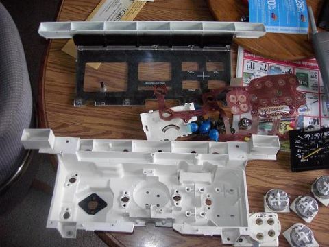 1980 Ford Bronco - A disassembled dashboard instrument cluster lies on a table, revealing its internal components and wiring.