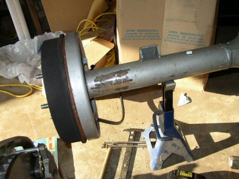 1995 Ford Bronco - Rear axle assembly with brake drum supported by jack stands, with cardboard boxes in the background.