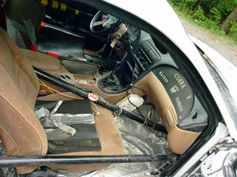 1995 Ford Mustang - Interior view of a 1995 Ford Mustang Cobra R, identified by 'Cobra R' and 'Hacker Express' badging on the dashboard, a roll cage.
