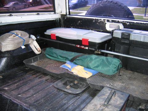 1992 Ford Bronco - The cargo area of a vehicle contains various items, including a toolbox and a rolled-up tow strap.