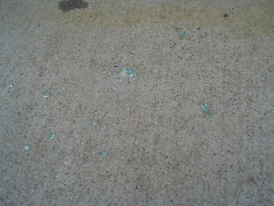 Bits of shattered green safety glass scattered across tan carpet