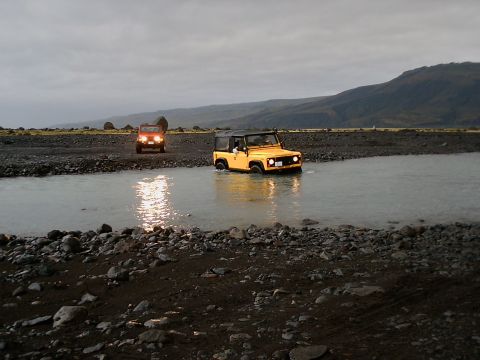 1996 Ford Bronco - Two 4x4 vehicles navigate a rocky riverbed under an overcast sky.