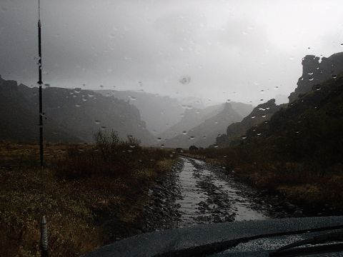 1996 Ford Bronco - Driving through a rocky mountain valley with rain on the windshield.