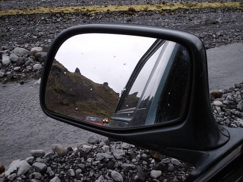 1996 Ford Bronco - Reflection in the side mirror reveals two off-road vehicles navigating a rocky, stream-filled landscape.