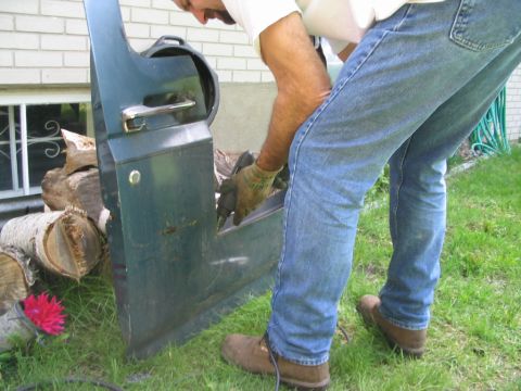 1986 Ford Bronco - A person is working on a vehicle door that has been removed from the vehicle.