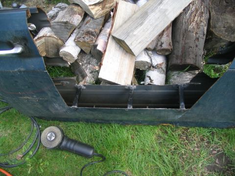 1986 Ford Bronco - A modified vehicle door is being used to store firewood, with an angle grinder on the grass.