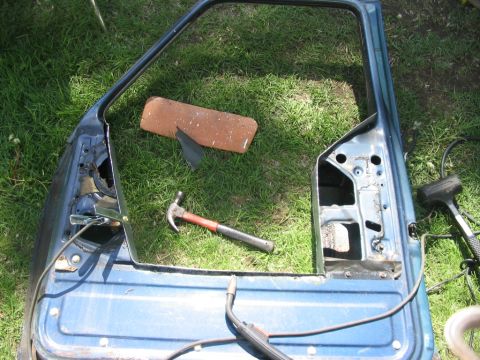 1986 Ford Bronco - A disassembled car door is on the grass, with tools nearby.