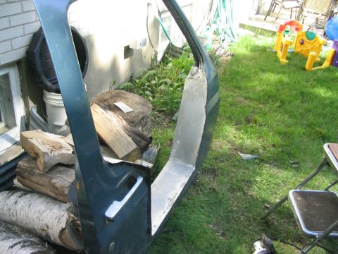 1986 Ford Bronco - A detached vehicle door is shown outdoors, with a background of a house and lawn.