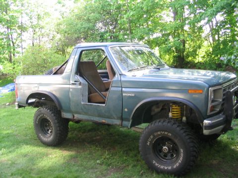 1986 Ford Bronco - This 1986 Ford Bronco features a lifted suspension and off-road tires, with its half doors removed for an open-air experience.