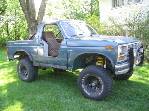1986 Ford Bronco - This modified Ford Bronco, seen from a 3/4 front angle, has had its doors removed and features an elevated suspension system.