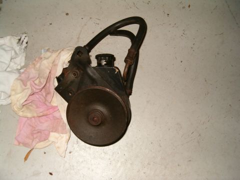 1979 Ford Bronco - A power steering pump assembly is shown, detached from a vehicle and resting on a concrete surface.