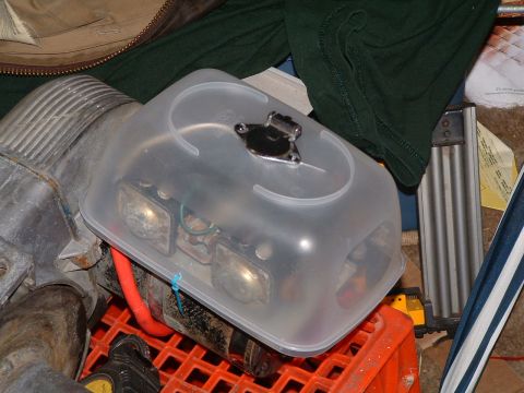 1979 Ford Bronco - A winch assembly is covered with a clear plastic container, showing internal components and a red cable.